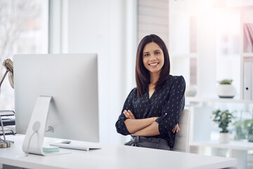 Arms crossed, computer and portrait of businesswoman at desk in office for administration career. Report, research and smile with happy employee in professional workplace for agency development