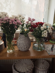 Chrysanthemum Bouquets in Progress: Vases and Blooms on a Wooden Kitchen Table, Vertical Close Up