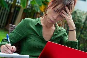 A woman is sitting on a chair and writing on a piece of paper