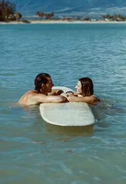 Couple resting on surfboard smiling