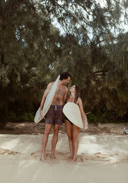 Happy surfer couple stand on beach