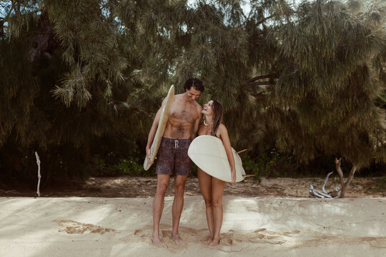 Happy surfer couple stand on beach