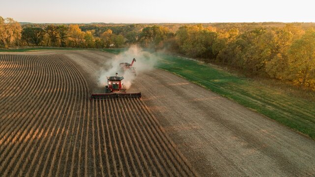Aerial view of a combine and tractor working on a field .