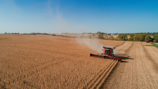 A combine in a large farm field during harvest.