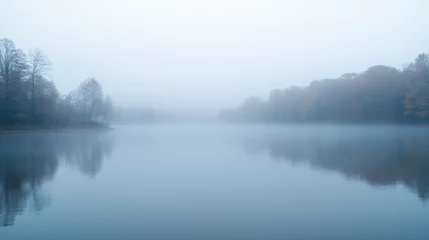 An early morning fog rising over a calm lake, creating a mystical atmosphere.