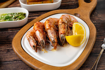 Red prawns or tiger prawns on a white plate with greens and tomatoes. Tiger shrimps