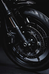 Cropped image of sport motorcycle wheel on dark background. Minimalistic shot of modern sport bike