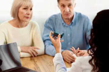 Doctor Holding Blue Asthma Inhaler For Treatment COPD Diseases For Senior Couple Patients