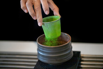 It was sifting matcha powder through a sieve into a teacup. A warm cup of matcha is made of finely ground green tea powder. It's widespread in Japanese culture
