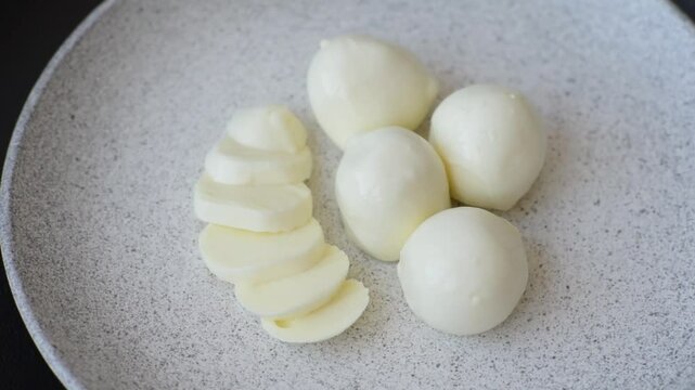 Delicious fresh mozzarella cheese with tomatoes, salt and spices on a dark concrete background