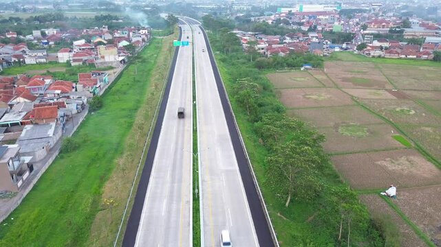 toll road Soreang pasir koja with Green rice filed background in west Java, Bandung Indonesia. Shot in 4k resolution from a drone flying upwards