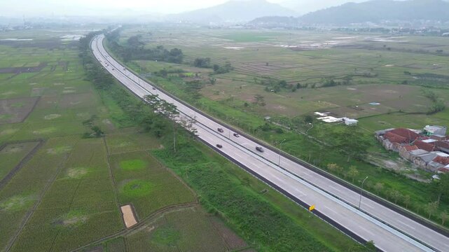 toll road Soreang pasir koja with Green rice filed background in west Java, Bandung Indonesia. Shot in 4k resolution from a drone flying upwards