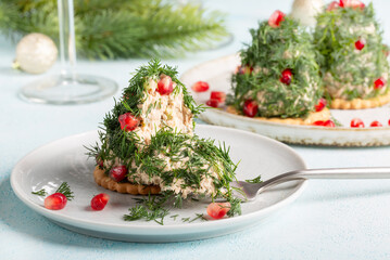 Portioned tuna pate on cracker decorated with dill and pomegranate seeds. Christmas appetizer in shape of Christmas tree.