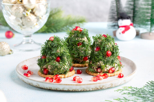 Portioned tuna pate on cracker decorated with dill and pomegranate seeds. Christmas appetizer in shape of Christmas tree.
