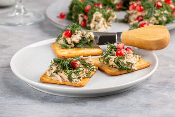Tuna pate decorated with dill and pomegranate seeds in shape of wreath served with crackers.