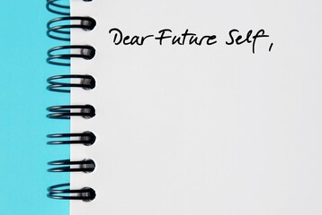 Notebook on blue background with handwritten text DEAR FUTURE SELF, a letter to convey message to...