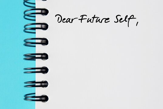 Notebook on blue background with handwritten text DEAR FUTURE SELF, a letter to convey message to future you. specific goals to achieve, follow up on bucket list items or declare important affirmation
