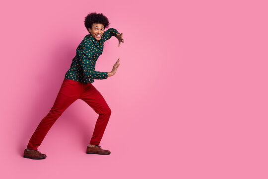 Full size photo of good mood positive guy with wavy hair dressed print shirt pushing object empty space isolated on pink color background