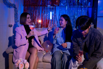 Three people are sitting on a couch, drinking wine and laughing