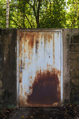 Rusty old iron gates on brick walls and barbed wire to block off the area.