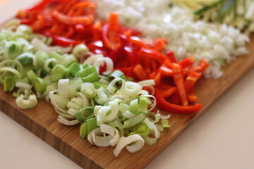 Chopped leek, red pepper, onion, zucchini and carrot on the chopping board. Cooking and meal prepping at home. Selective focus.