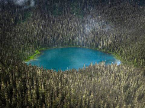 Aerial view of serene forest and picturesque lake surrounded by clouds, Agassiz, Canada.