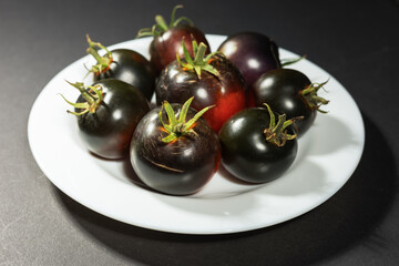 Cumato black tomatoes in a white plate. Black tomato.