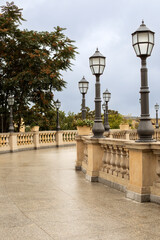 Fototapeta premium city ​​autumn street after the rain with yellow balustrade and lanterns and autumn trees on a cloudy autumn day after the rain 