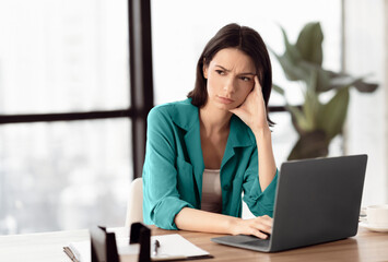 Lack Of Motivation. Portrait of stressed upset female student working on computer at home, looking away, copyspace