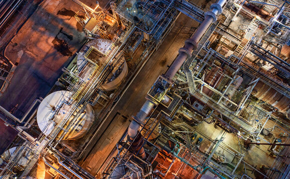 Aerial view of an industrial oil refinery complex with intricate pipes and tanks illuminated at night, Richmond, California, United States.
