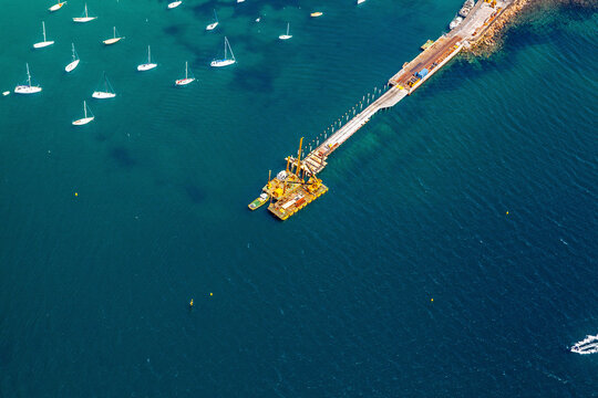 Aerial view of Schnapper Point with serene blue water, boats, and a pier, Mornington, Victoria, Australia.