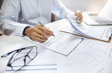 Asian businessman reviewing document report at office working with laptop. legal expert,...