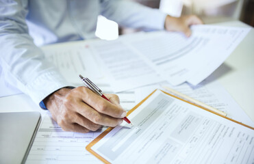 Close-up shot, asian businessman reviewing document reports at office workplace. legal expert, professional lawyer reading and checking financial documents or insurance contract before sign