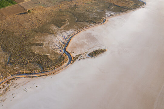 Aerial view of expansive salt farm landscape with serene water and sandy terrain, Dazkiri, Turkey.