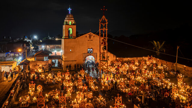 Aerial view of a vibrant cemetery illuminated by candles during the day of the dead celebration, ErongarIcuaro, Mexico.