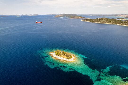 Aerial view of Otocic Krbelica island surrounded by turquoise sea and beautiful coastline, Bilo, Croatia.