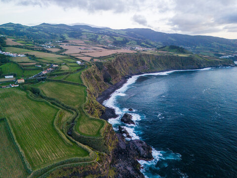 Aerial view of beautiful coastline with green fields and rocky cliffs overlooking the ocean, Miradouro Maia, Sao Miguel Island, Portugal.