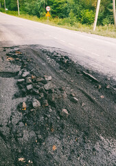 asphalt broken by trucks in a wooded area far from the city