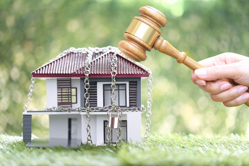 Property auction, Woman hand holding gavel wooden and locked house with padlock and chain on...