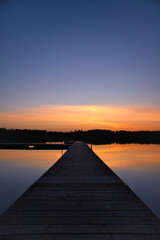 Wooden jetty at sunset on a Swedish lake. Sunset reflected in the water