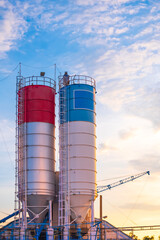Cement storage silos in industry manufacturing factory area against evening sky background in vertical frame
