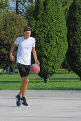 Boy playing basket ball on outdoors basket court.