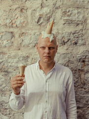 Bald man with ice cream on his head, on an old street in Italy, Montenegro, Croatia. Horns with melted ice cream stuck on his head.