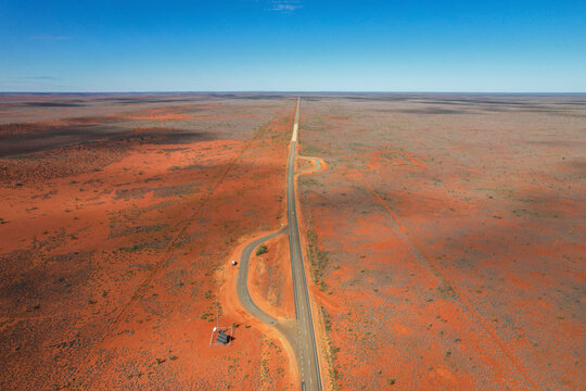 Aerial view of a vast arid desert landscape with Burkett Road and a campervan, Gascoyne Region, Australia.