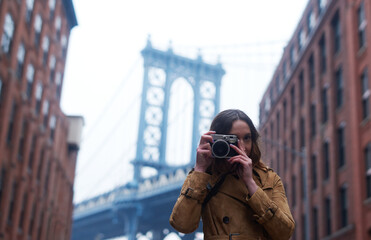 Fototapeta premium Travel, photography and woman with camera in city for creative hobby, adventure and holiday memory. Outdoor, portrait and person with DSLR equipment for sightseeing, pictures and vacation in New York