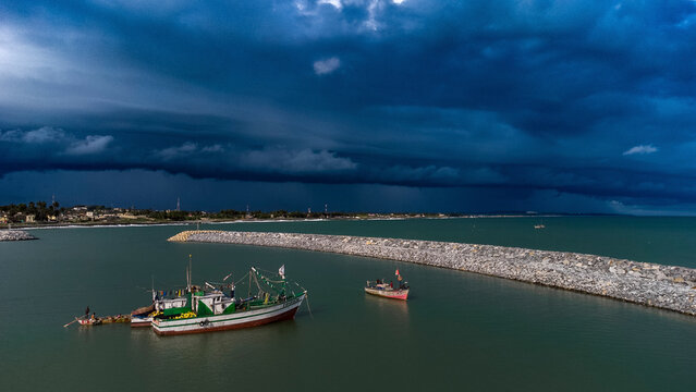 Aerial view of fishing boats in a stormy ocean under dark clouds, Elmina, Ghana.