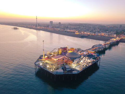 Aerial view of brighton pier at sunset with beautiful reflections on the sea, brighton, united kingdom.