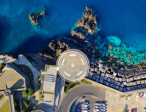 Aerial view of scenic coastal landscape with helicopter land platform and turquoise ocean, Porto Moniz, Portugal.