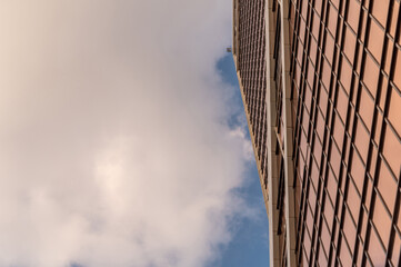 Angled view of modern skyscrapers in business district against blue sky. Looking Up high-rise office buildings. Evening time, sunset. Orange, yellow and gold shades of color.
