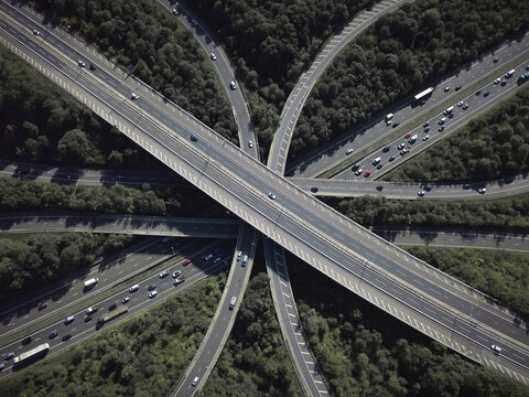 Aerial view of a busy highway intersection with winding roads amidst greenery and urban infrastructure, Bletchingley, England.